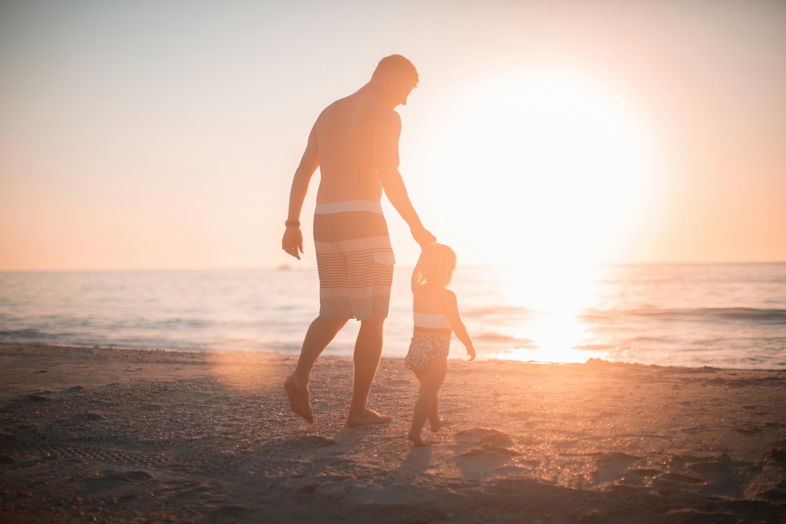 father walking with his son at the beach at sunset
